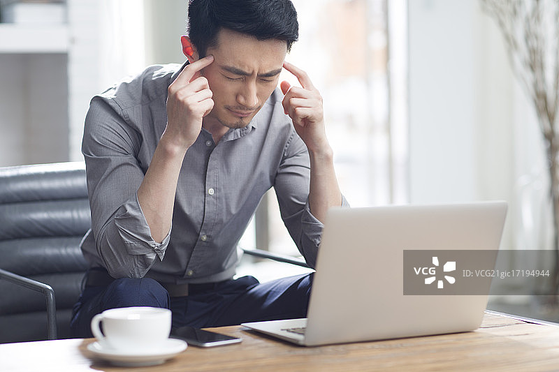 疲劳的年轻男子在办公室工作图片素材