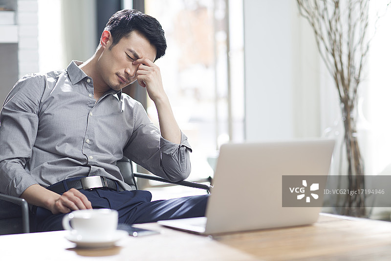 疲劳的年轻男子在办公室揉眼睛图片素材