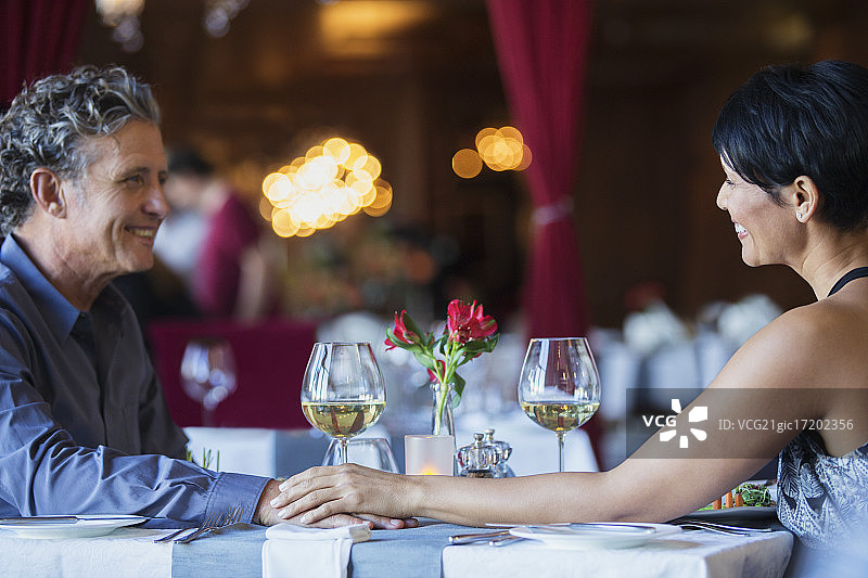 中年夫妇在餐厅的桌子旁面对面坐着并手牵着手图片素材