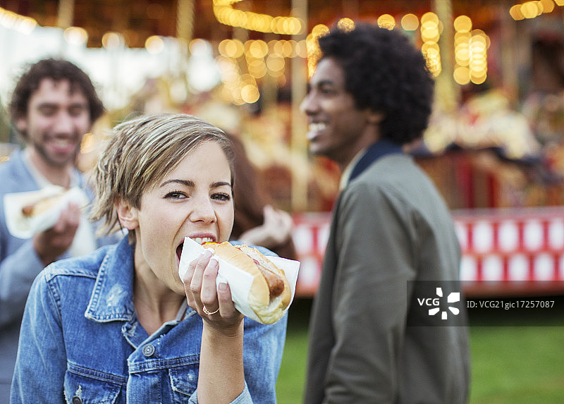 三个年轻人在游乐园吃热狗图片素材