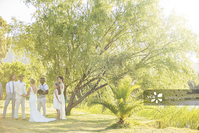 年轻夫妇和客人们站在花园里参加婚礼图片素材