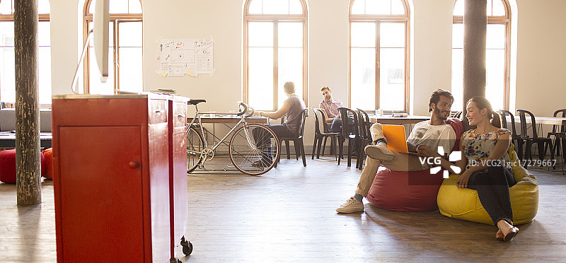 在开放式办公室使用笔记本电脑工作的商务人士图片素材