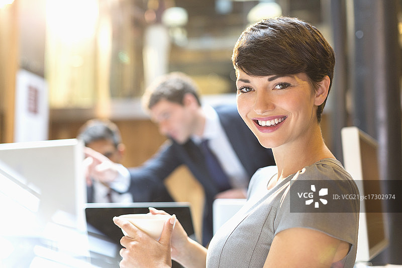 在办公室喝咖啡的自信女商人肖像图片素材