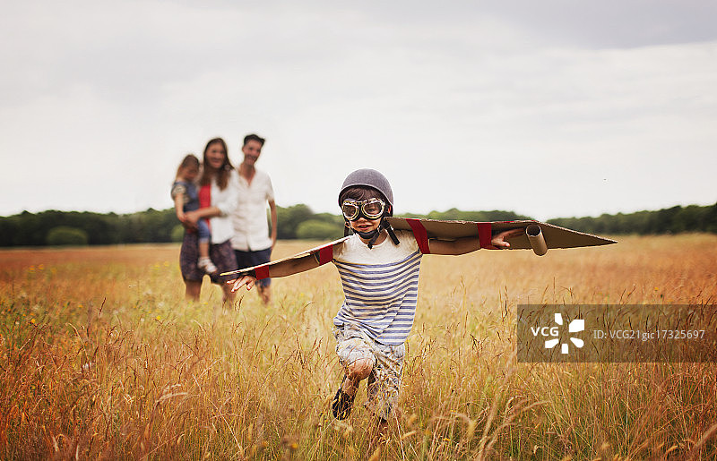 戴着飞行帽和护目镜的男孩在田野里玩耍图片素材