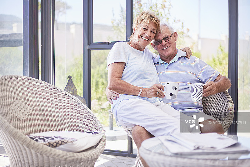 微笑的老年夫妇在阳光房里喝咖啡的肖像图片素材