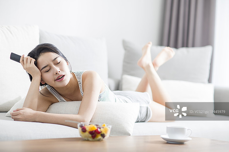 年轻女子在沙发上看电视图片素材