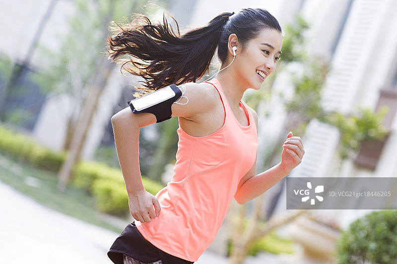 年轻女子在户外边听音乐边跑步图片素材