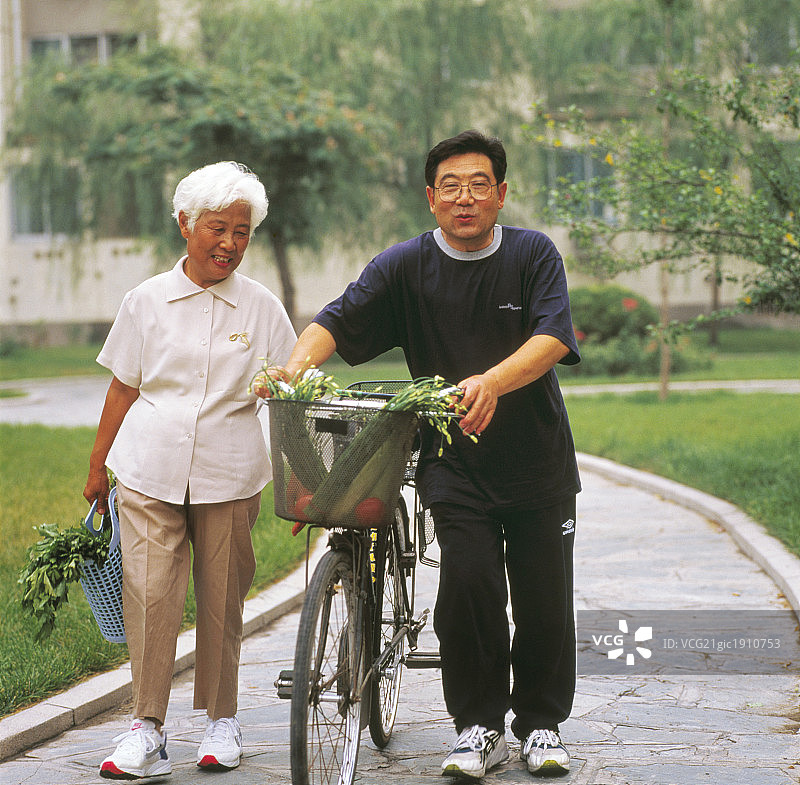 东方老年夫妇在户外推着自行车买菜图片素材