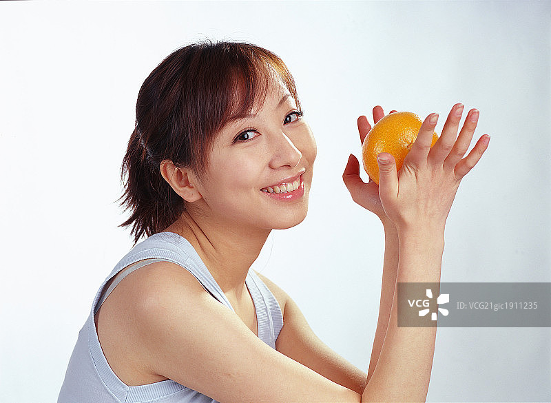 东方女人在室内坐着手拿水果图片素材