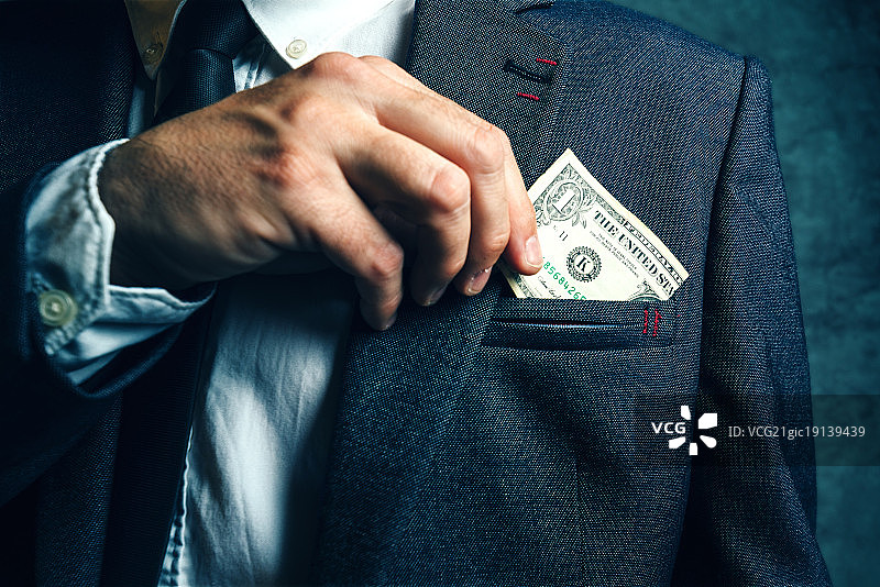 商人将美元钞票放入西装口袋图片素材
