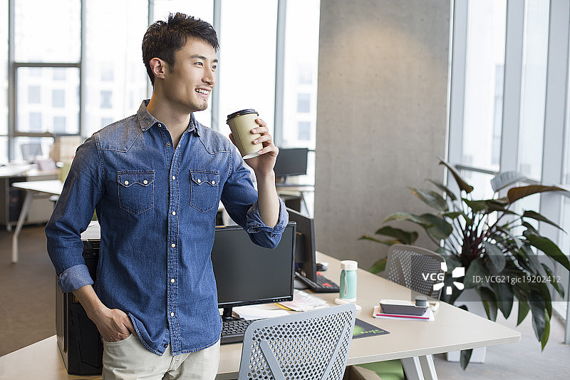 年轻男子在办公室喝咖啡图片素材
