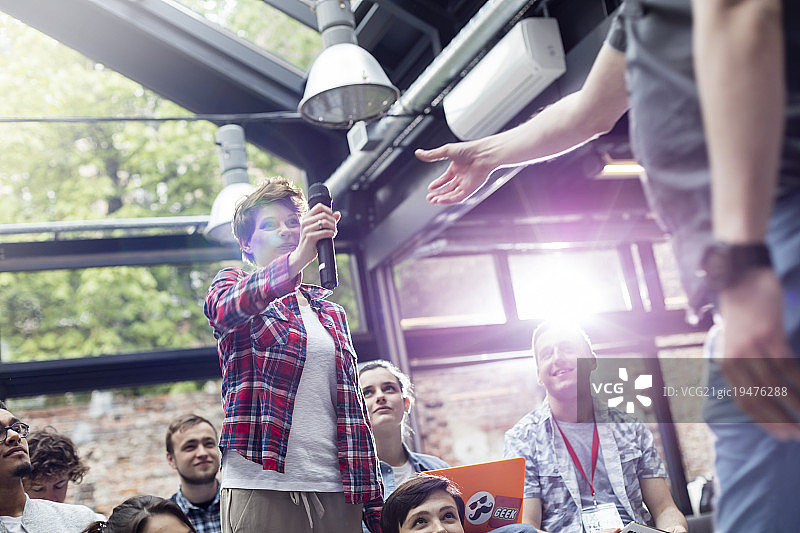 在会议上递麦克风给演讲者的女人图片素材