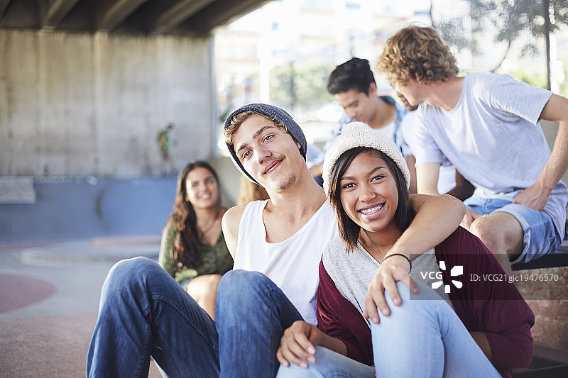 微笑青少年情侣和朋友在滑板公园玩耍图片素材