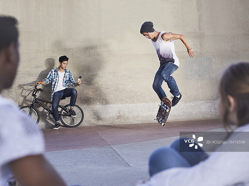 朋友们在滑板公园观看少年玩滑板图片素材