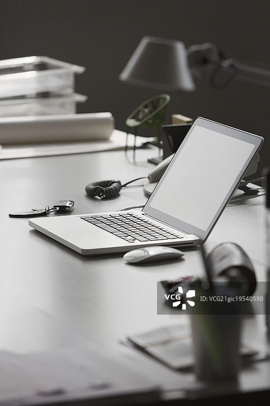 办公室桌子上的笔记本电脑和车钥匙图片素材