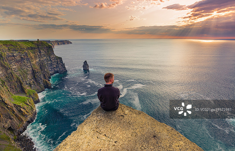 一个人坐在英国爱尔兰莫赫悬崖上图片素材