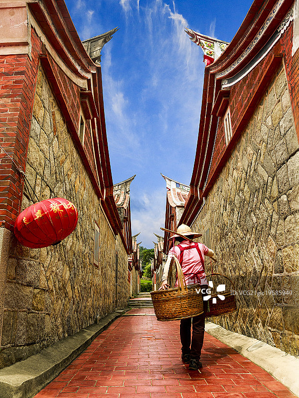 金门，一位提着篮子的妇女经过一座寺庙。图片素材