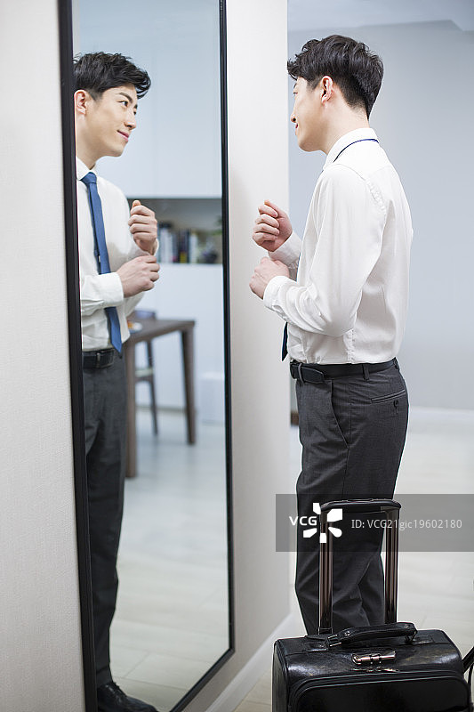 年轻男子在镜子前检查着装图片素材