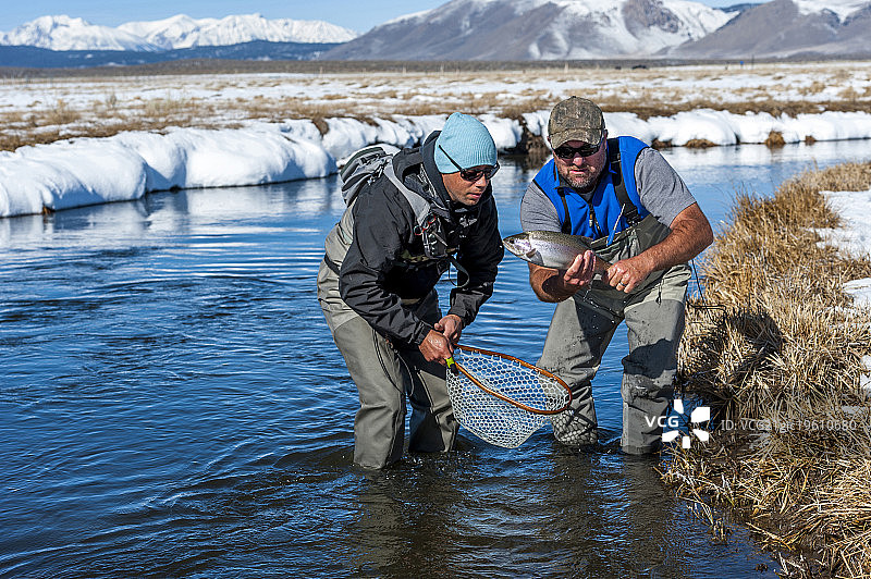 两名渔民在上欧文斯河捕获一条虹鳟鱼图片素材