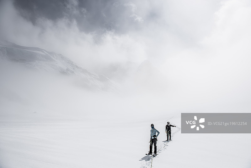 两名登山者在鲁斯冰川低能见度下行进图片素材