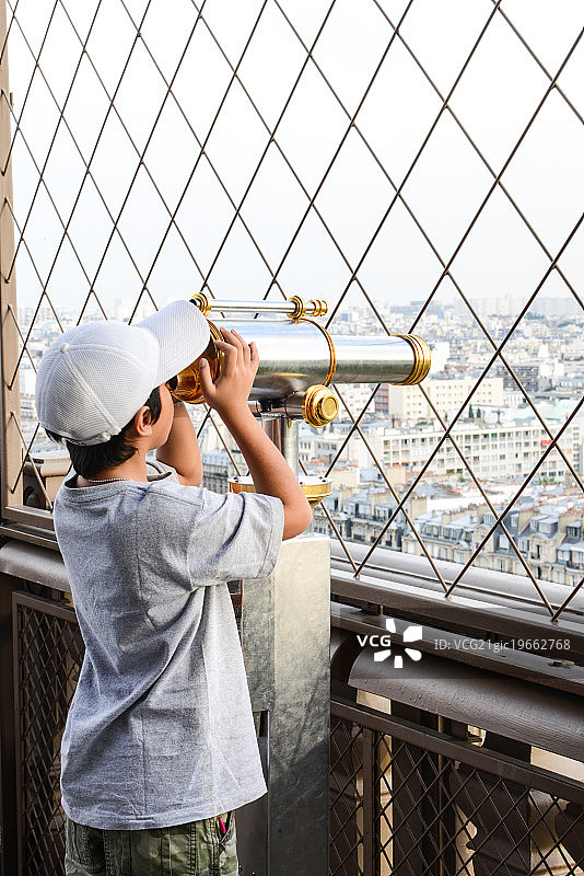 男孩在埃菲尔铁塔使用双筒望远镜图片素材