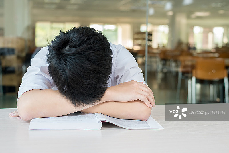 亚洲男学生在大学的演讲厅里坐着睡觉图片素材