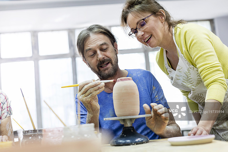 在工作室里绘制陶器的中年夫妇图片素材