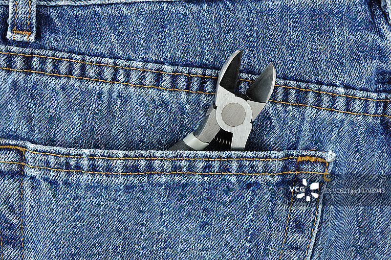蓝色牛仔裤口袋里的斜口钳图片素材