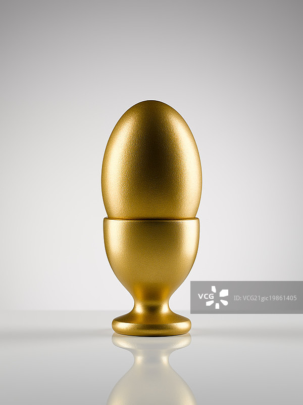 白色背景下的蛋杯中的金蛋图片素材
