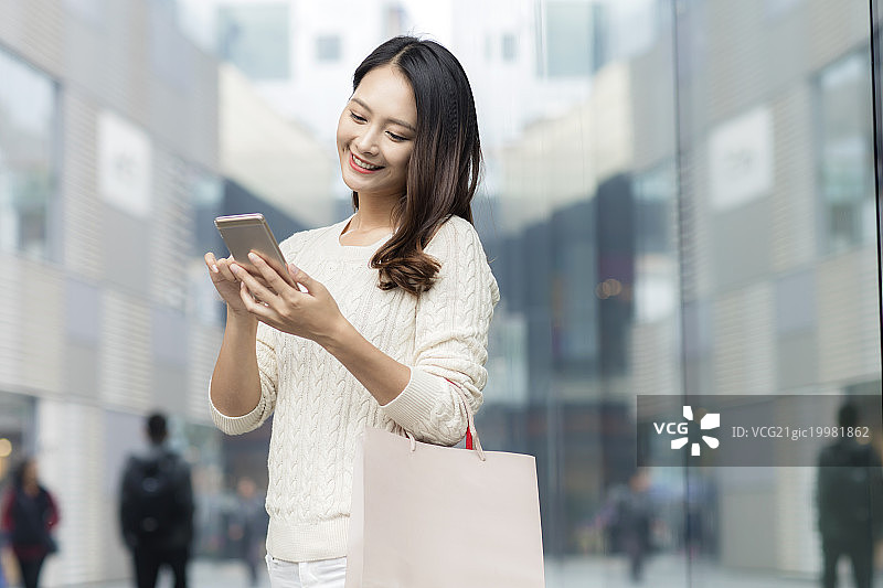 拎着购物袋打电话的青年女人图片素材