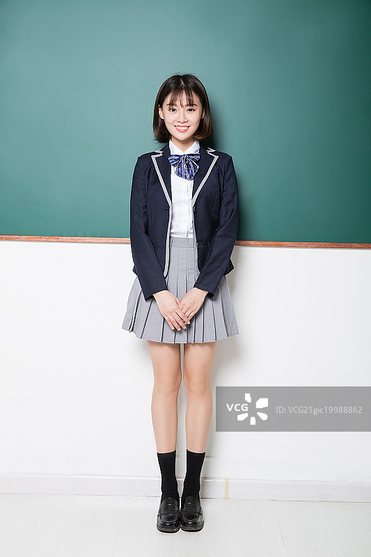 一名漂亮的女高中生靠着黑板站着图片素材