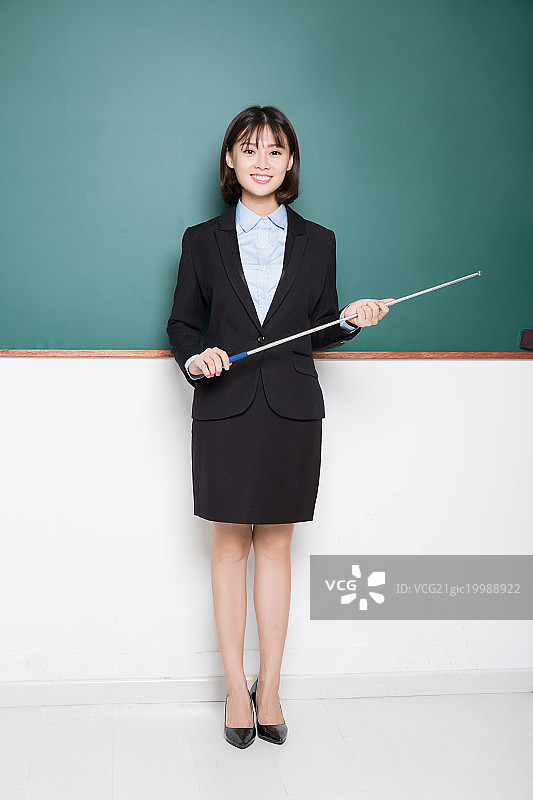 手持教棒的女教师,在黑板前图片素材