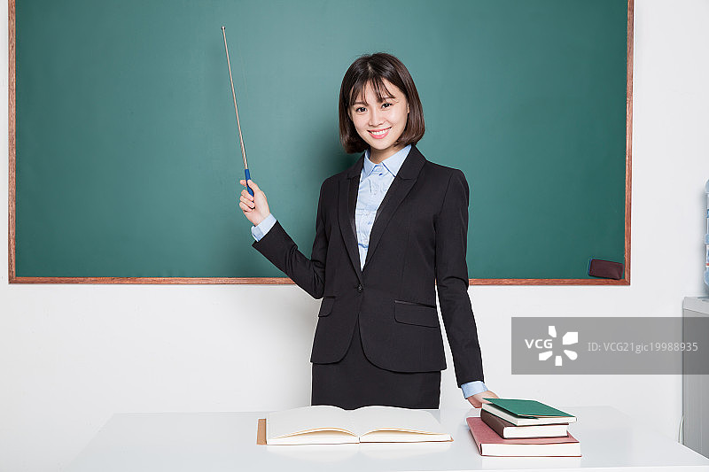 手持教棒的女教师,在黑板前图片素材