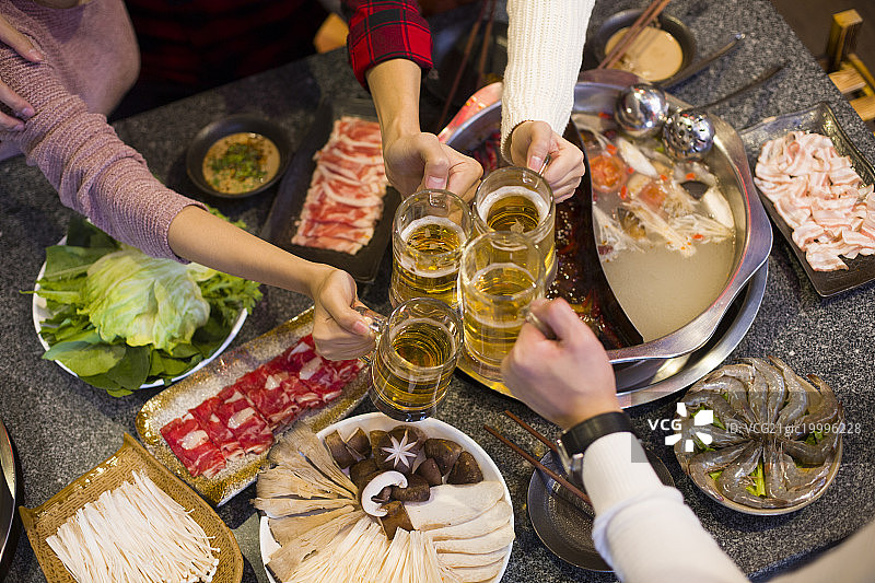 年轻朋友们在火锅店吃饭喝啤酒图片素材