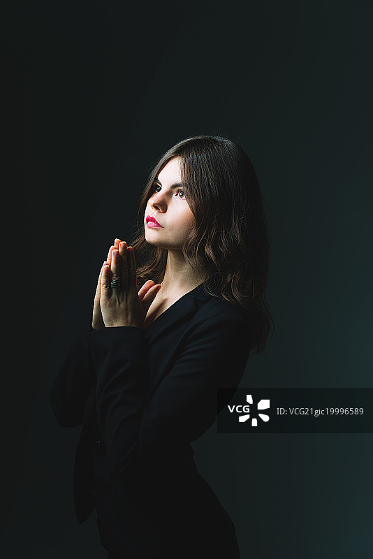 影棚拍摄的双手合十的祈祷少女图片素材