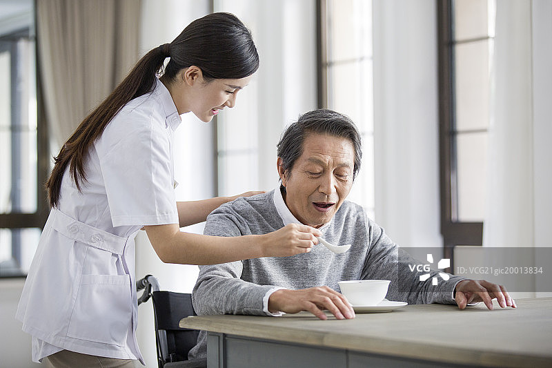 护工照顾坐着轮椅的老年男子图片素材