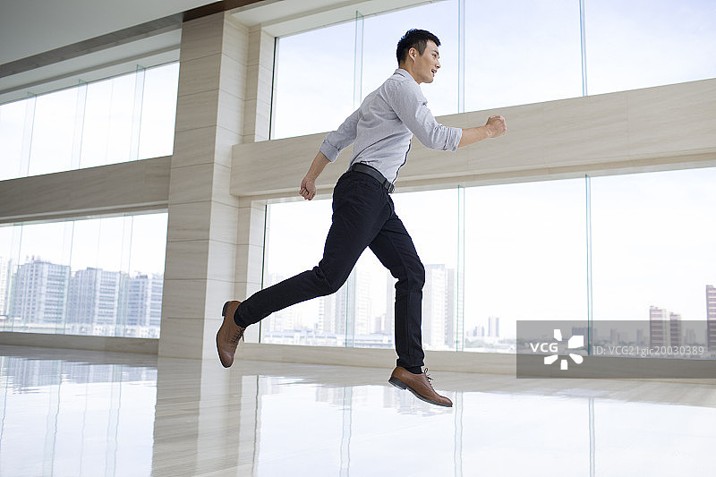 年轻商务男子在办公楼内空中奔跑图片素材