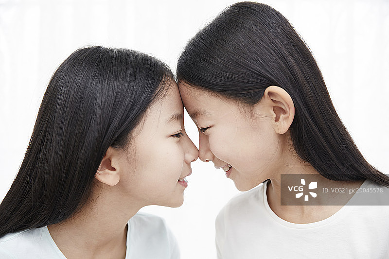 双胞胎姐妹看着对方，鼻子接触，侧视图图片素材