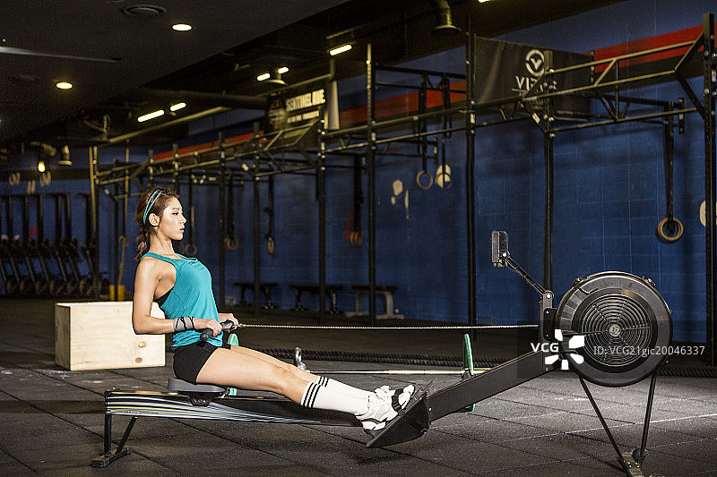 女人在健身房的划船机上锻炼（侧视图）图片素材