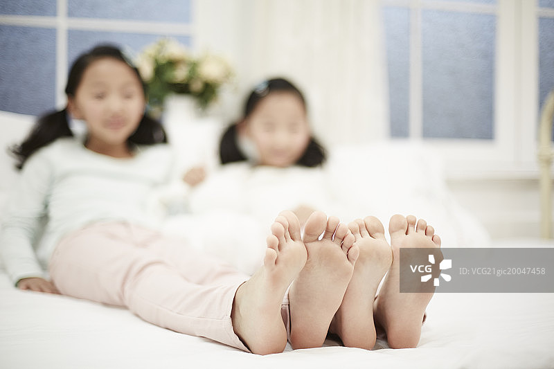 两个女孩伸直双腿坐在床上图片素材