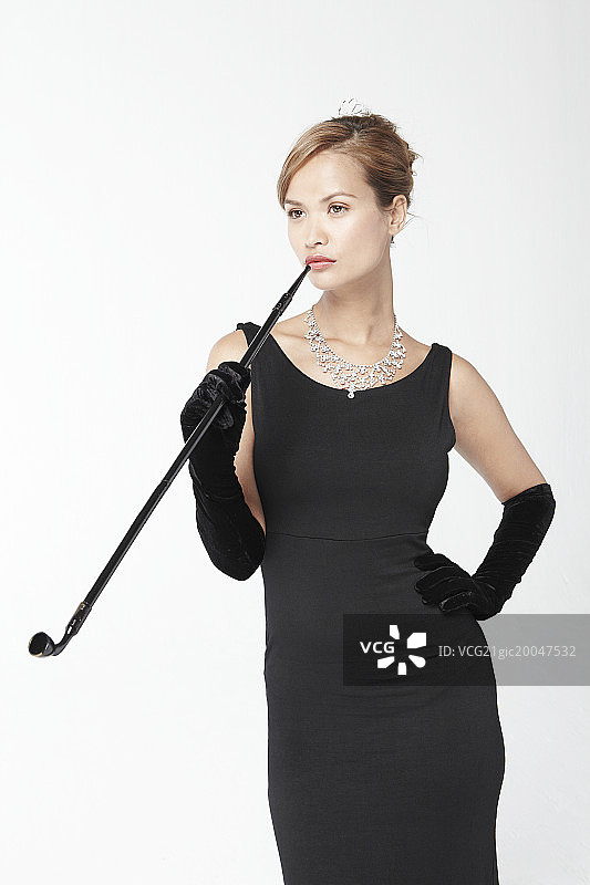 身穿黑色连衣裙，手持烟斗的女人图片素材