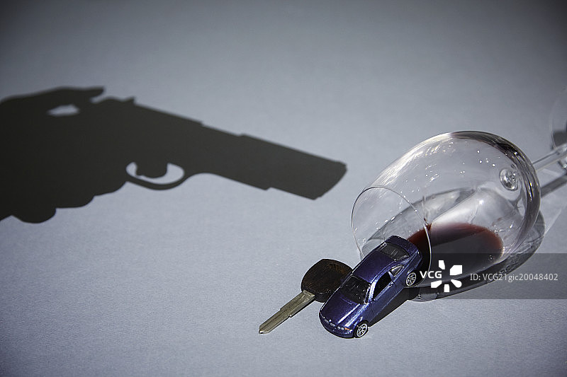 手持枪指向酒杯和车钥匙的轮廓图片素材