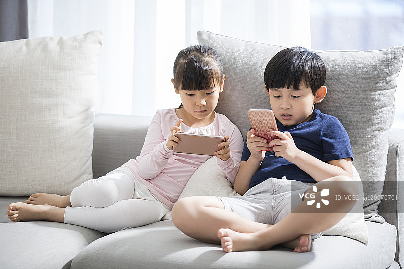 小男孩和小女孩在沙发上玩手机图片素材