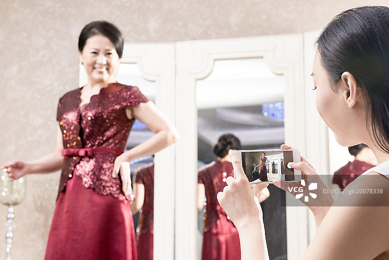 Mature woman trying on dress in boutique图片素材