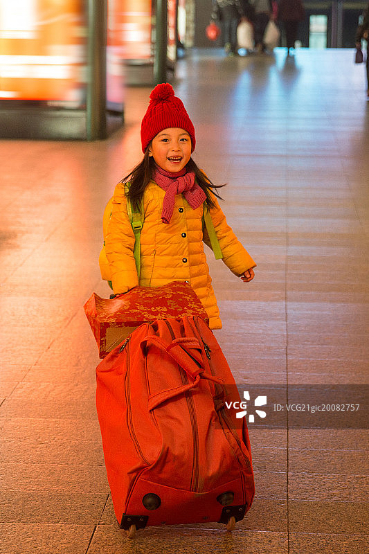 小女孩拉着行李箱在候车厅图片素材