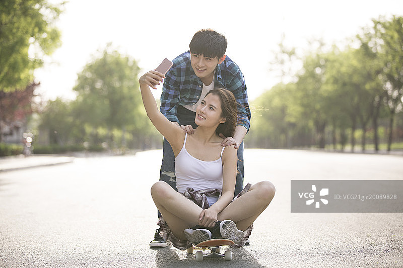 滑滑板的情侣用手机自拍图片素材