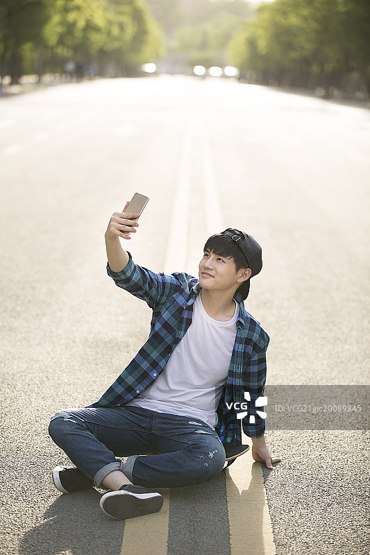 滑滑板的男子用手机自拍图片素材