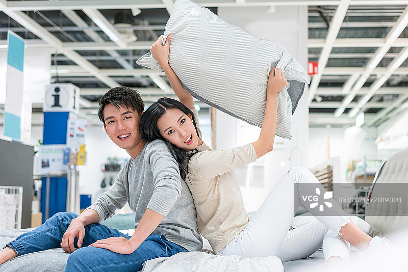 年轻情侣背靠背坐在床上图片素材