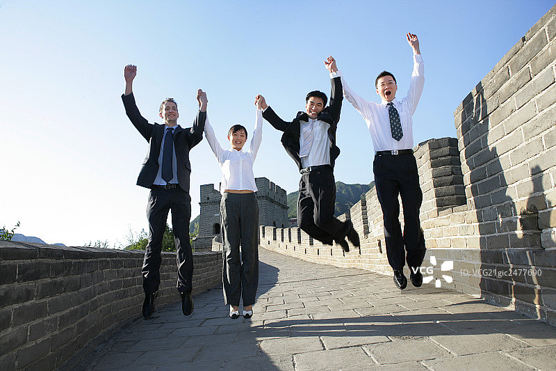 四位中外商务人士在长城上跳跃欢呼图片素材