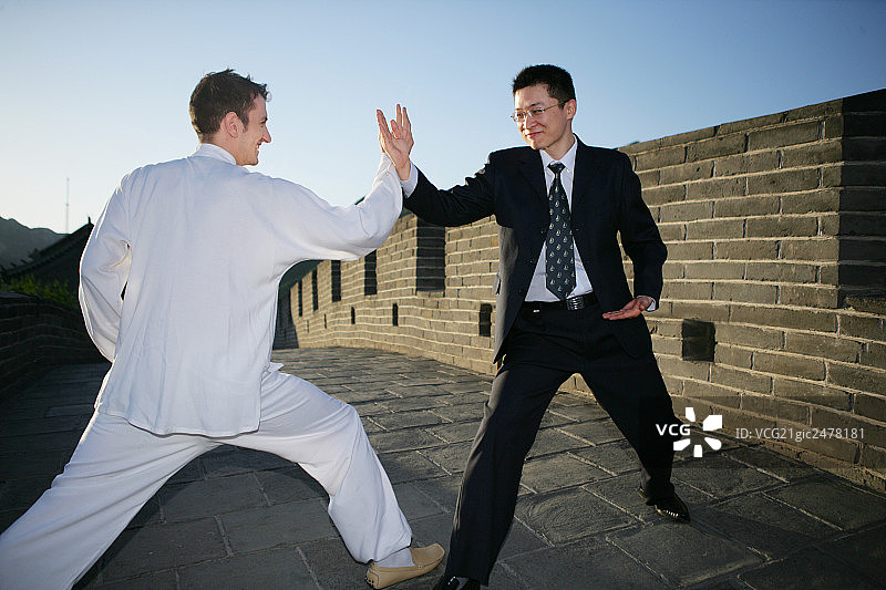 穿中式传统服装的外国人和中国商务人士在长城上比武图片素材